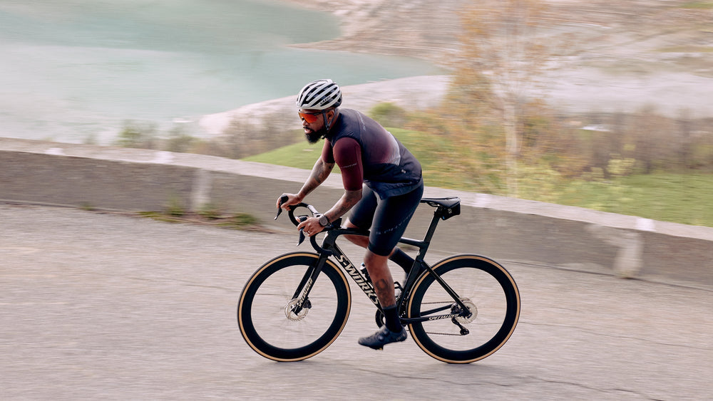 Man riding a Specialized Tarmac Road bike wearing a Lazer Z1 Kineticore bike helmet up a hill