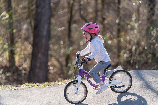 Little girl riding her bike wearing a Lazer Pnut KinetiCore kids bike helmet